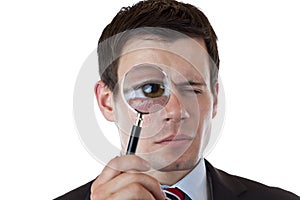 Businessman with magnifying glass at eye