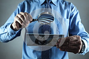 Businessman with magnifying glass and money. Search money