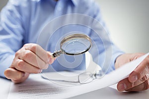 Businessman with magnifying glass reading documents photo