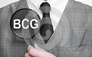 Businessman with magnifying glass on the white background. BCG sign