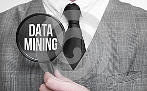 Businessman with magnifying glass on the white background. DATA MINING sign