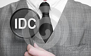 Businessman with magnifying glass on the white background. IDC sign