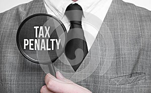 Businessman with magnifying glass on the white background. TAX PENALTY sign