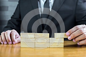 Businessman make a building with wood blocks