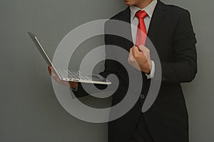 Businessman make enthusiastic hand gestures celebrating his achievement and holding laptop