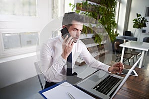 Businessman making a call and working on laptop in the office