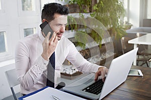 Businessman making a call and working on laptop in the office