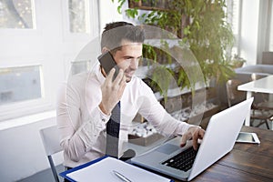 Businessman making a call and working on laptop in the office