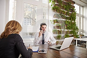 Businessman with making a call and working on laptop while sitting in the office