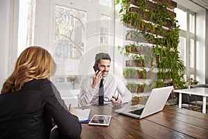 Businessman with making a call and working on laptop while sitting in the office