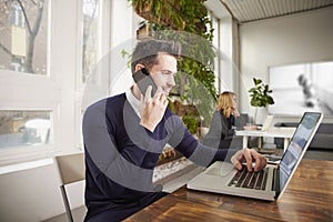 Businessman with making a call and working on laptop while sitting in the office