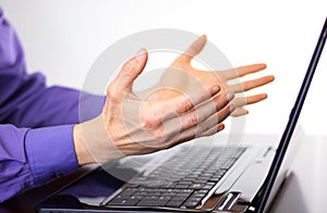 Businessman making hand gesture `come on` in front of laptop display.