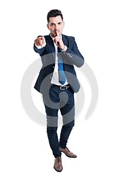 Businessman making keep a secret gesture standing on white backg