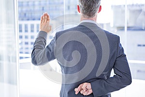 Businessman making a oath while crossing fingers photo