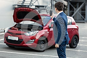 Businessman making photo on phone of breakdown car for insurance