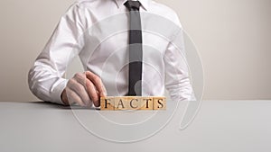 Businessman making a sign Facts with wooden cubes