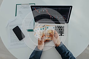 Businessman man counting euro money working on computer at office desk, inflation concept., top view.