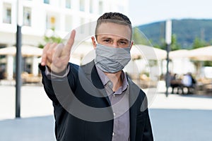 Businessman man with face mask as protection against corona virus infection gesturing stop