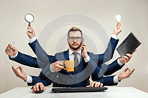 Businessman with many hands in a suit. Works simultaneously with several objects, a mug, a magnifying glass, papers, a contract, a photo