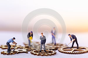 Businessman and many workers standing on wooden gear.