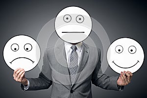 Businessman with mask of different emotions. Businessman holding smile and sad mask. Conceptual image of a man changing his mood f