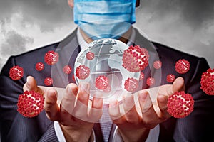 A businessman in a mask supports a globe infected by the coronavirus photo