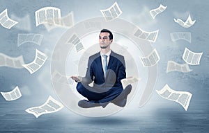 Businessman meditating with flying paper concept