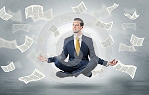 Businessman meditating with flying paper concept