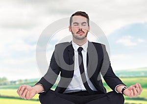 Businessman Meditating by green fields