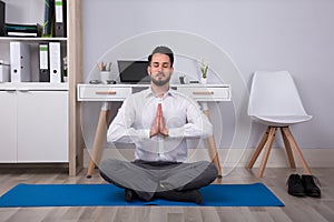 Businessman Meditating In Office