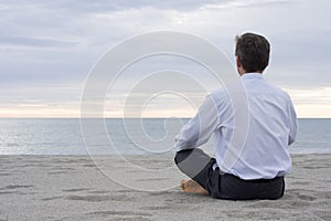 Businessman meditating at the sea