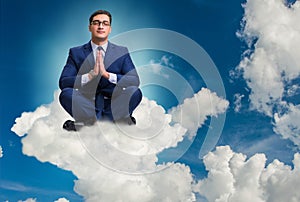 Businessman meditating in the sky