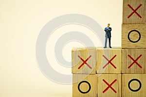Businessman miniature standing and thinking on o x board games. Tic Tac Toe photo