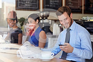 Emprendedor móvil teléfono a periódico en café la tienda 