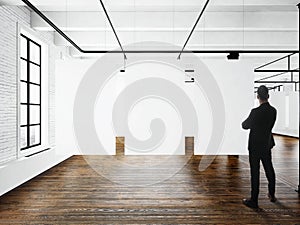 Businessman Modern art museum expo loft interior.Open space studio.Empty white canvas hanging.Wood floor,bricks wall