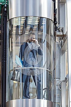 Businessman in modern glass elevator