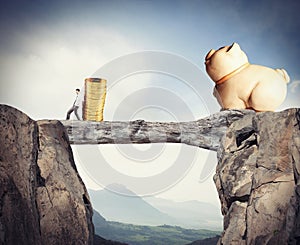 Businessman moves a pile of coins to a moneybox. concept of difficulty to saving money