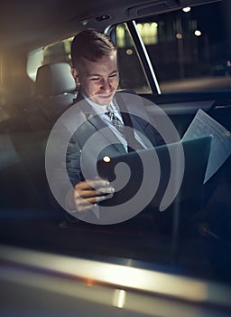 Businessman in moving car checking his working on laptop