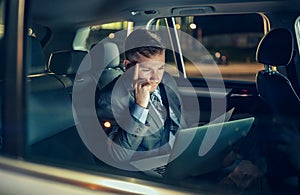 Businessman in moving car working on his laptop