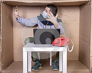 Businessman negotiating by phone, sitting in a cardboard office, screams