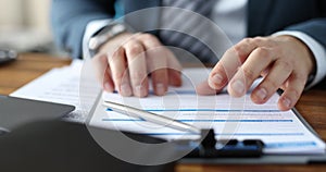 Businessman nervously tapping fingers on contract at table closeup