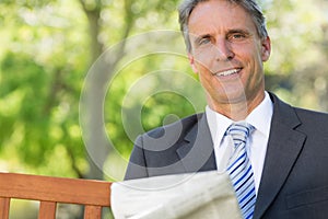 Businessman with newspaper in park photo