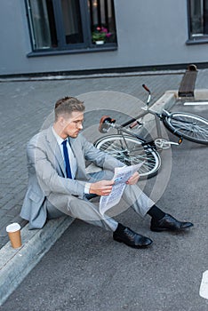 Businessman newspaper while sitting near takeaway