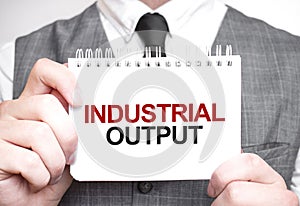 Businessman with notebook with text INDUSTRIAL OUTPUT