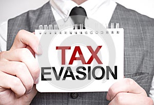 Businessman with notebook with text TAX EVASION