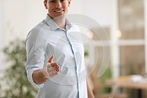 Businessman offering handshake in office, closeup.