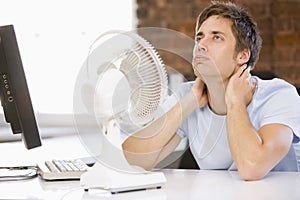 Businessman in office with computer and fan