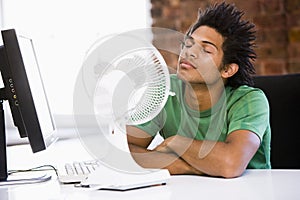 Businessman in office with computer and fan