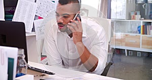 Businessman In Office At Desk Talking On Mobile Phone