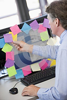 Businessman in office at monitor with notes on it